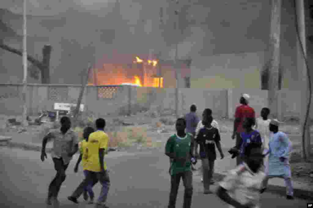 Smoke rises from the police headquarters as people run for safety in Nigeria's northern city of Kano January 20, 2012.