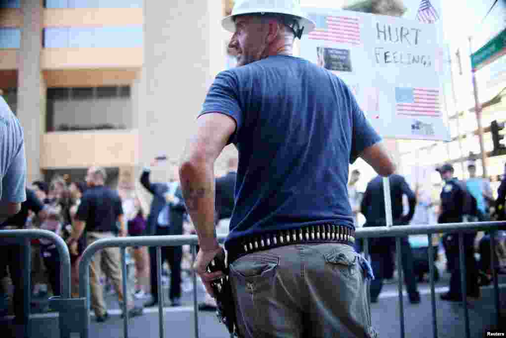 A Pro Trump supporter holds a fire arm as he faces off with peace activists during protests outside a Donald Trump campaign rally in Phoenix, Ariz., Aug. 22, 2017.