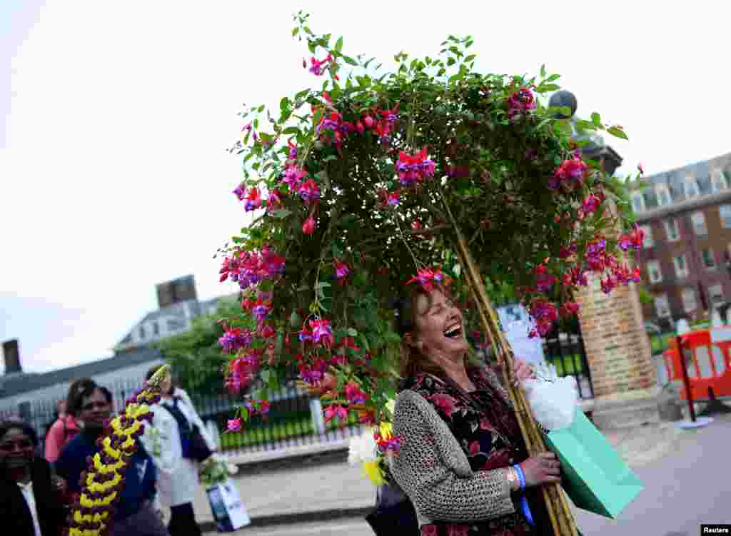 A woman carries a fuschia plant on the final day of the Royal Horticultural Society&#39;s Chelsea Flower Show in London, Britain, May 23, 2015.