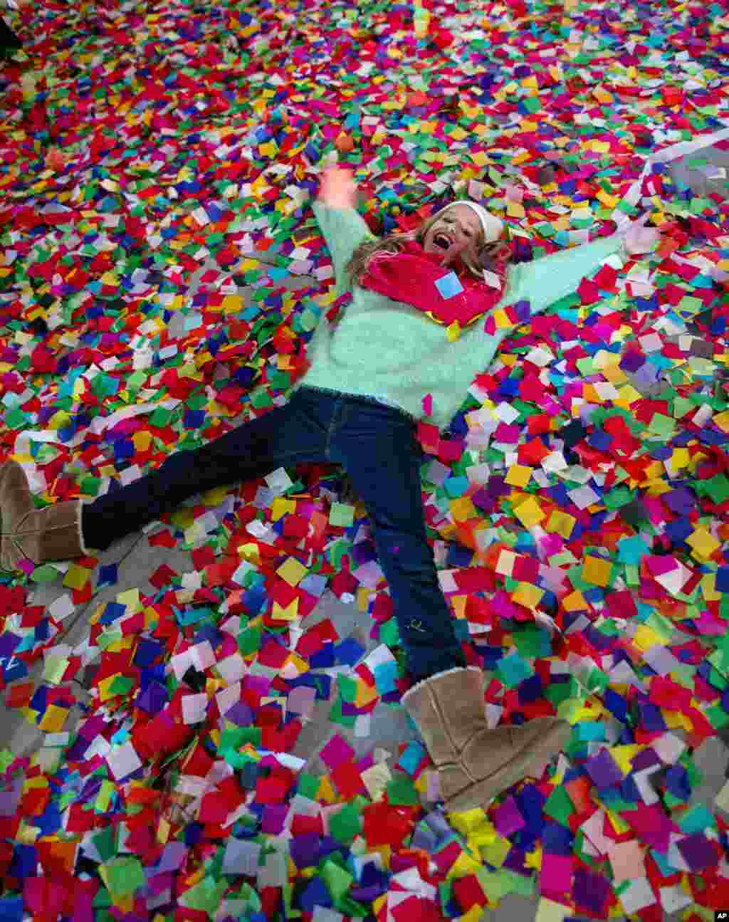 Nicole Tacher, 11, lays in confetti on a hotel balcony as the new year is celebrated, Times Square, New York City, New York, Jan. 1, 2014.