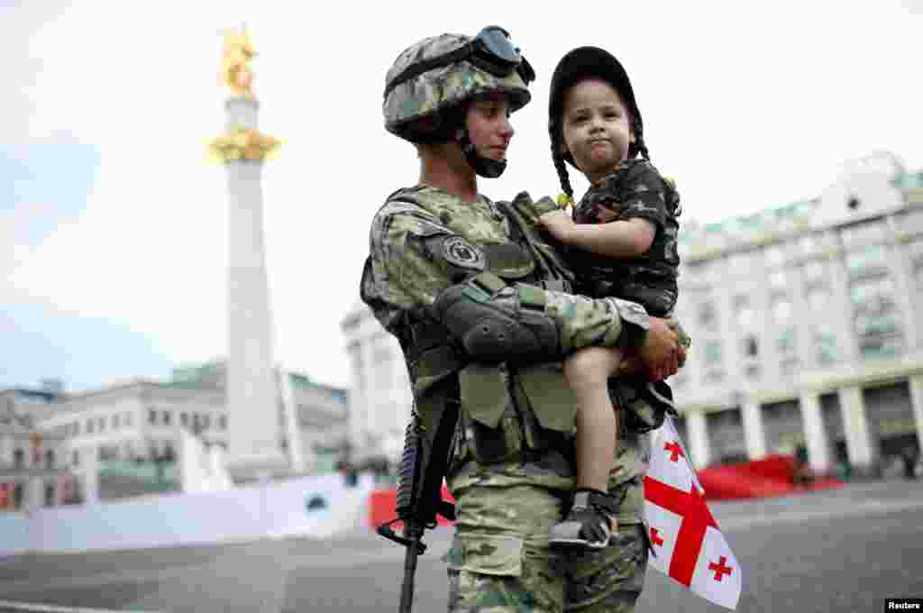 Servicewoman, Tamar Kurkumuli, 25, holds her 3-year-old daughter Nino, before the oath-taking ceremony as Georgia marks the 100th anniversary of its independence in Tbilisi, Georgia, May 26, 2018.