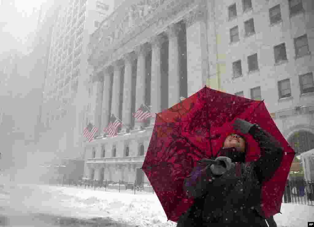 Jessica Ourisman looks up at the buildings around the New York Stock Exchange while touring lower Manhattan during a snow storm, Saturday, Jan. 23, 2016, in New York. (AP Photo/Julie Jacobson)