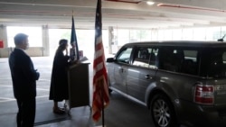 In this Friday, June 26, 2020 photo, U.S. District Judge Laurie Michelson, center, administers the Oath of Citizenship during a drive-thru naturalization service in a parking structure at the U.S. Citizenship and Immigration Services office.