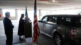 In this Friday, June 26, 2020 photo, U.S. District Judge Laurie Michelson, center, administers the Oath of Citizenship during a drive-thru naturalization service in a parking structure at the U.S. Citizenship and Immigration Services office.