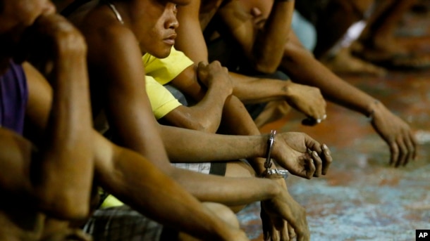 FILE - Rounded up residents, mostly males, wait to be transported to a police station in the continuing operation of President Rodrigo Duterte's so-called "War on Drugs" campaign, at the slum community of Tondo, in Manila, Philippines, Sept. 30, 2016.