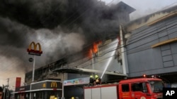 Nhân viên cứu hỏa chật vật tranh đấu để kiềm chế đám cháy lớn bùng phát tại một trung tâm mua sắm Philippines ngày 23/12/2017, ở t.p. Davao, miền Nam Philippines. 
