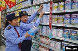 FILE - Chinese commercial law enforcement personnel inspect milk powder products at a supermarket in Lianyungang, Jiangsu province, China.