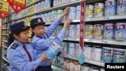 FILE - Chinese commercial law enforcement personnel inspect milk powder products at a supermarket in Lianyungang, Jiangsu province, China.