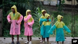 Girls wear matching raincoats as they wait along a roadside during a rain shower in Bata, Equatorial Guinea, (File photo).
