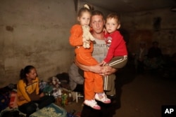 FILE - A local resident holds his children in a basement which is being used as a shelter following shelling in Donetsk, eastern Ukraine.