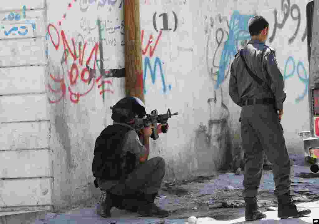 An Israeli soldier aims his gun at Palestinian protesters during clashes in Hawara village near the West Bank city of Nablus, July 25, 2014.&nbsp;