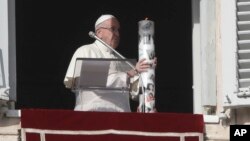Pope Francis holds a candle decorated with the faces of Syrian children suffering from war during the Angelus noon prayer St. Peter's Square at the Vatican, Dec. 2, 2018. 