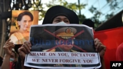 A Myanmar migrant holds up a poster with the image of Myanmar's Chief Senior General Min Aung Hlaing, commander-in-chief of the Myanmar armed forces, as they take part in a demonstration outside the Myanmar embassy in Bangkok on February 1, 2021.