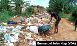 Des tas d'ordures barrent la route au lieu dit, derrière l'office du baccalauréat. Pas de bacs à ordures ici pour une forte population du quartier, à Yaoundé, au Cameroun, le 23 mai 2017. (VOA/Emmanuel Jules Ntap)