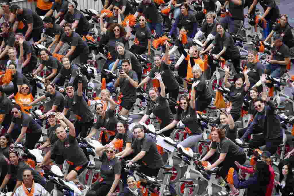 Participants wave during the Cycle for Survival kick-off event as instructors lead rides in New York's Times Square. Cycle for Survival is a national movement to raise funds to beat rare cancers. More than $50 million has been raised since its founding in 2007.