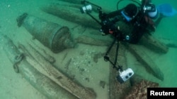 A divers takes photos of some of the items found after the discovery of a centuries-old shipwreck, in Cascais, Portugal, Sept. 24, 2018.