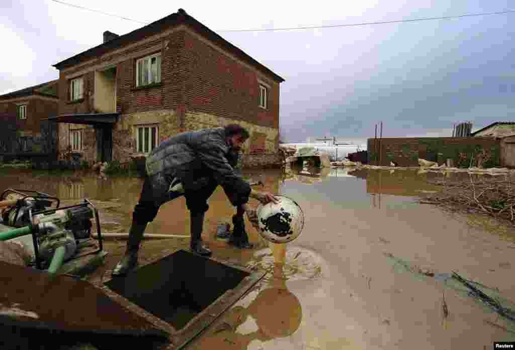 Makedonac iz Murtina skuplja vodu ispred njegove popljavljene kuće.