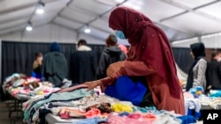 FILE - Afghan refugees pick out clothes at an Afghan refugee camp at Joint Base McGuire Dix Lakehurst, N.J., Sept. 27, 2021. 
