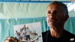 Tunisian man shows a photograph of his relative, who died while trying to reach Italy illegally, at coastal town Zarzis in southeastern Tunisia, February 18, 2011