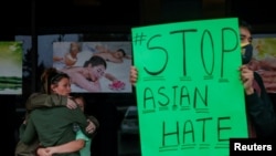 People grieve while Jesus Estrella, 21 holds a sign outside Young's Asian Massage