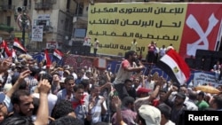 Supporters of Egyptian President-elect Mohamed Morsi rally in front of a banner rejecting recent military edicts at Tahrir square in Cairo, June 26, 2012. 
