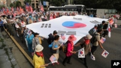 People carry a huge South Korean national flag during a rally to mark the 67th anniversary of the Korean War in Seoul, South Korea, June 25, 2017.
