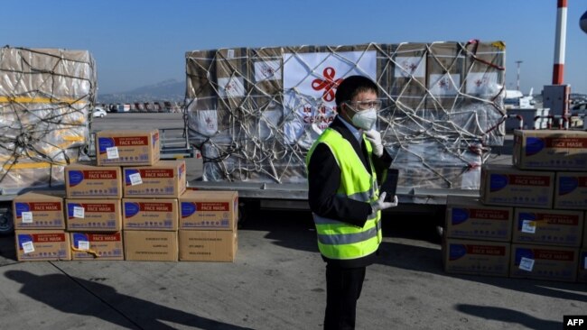 希腊雅典国际机场的一名工人站在从中国运抵的口罩等抗疫防护用品。(2020年3月21日)