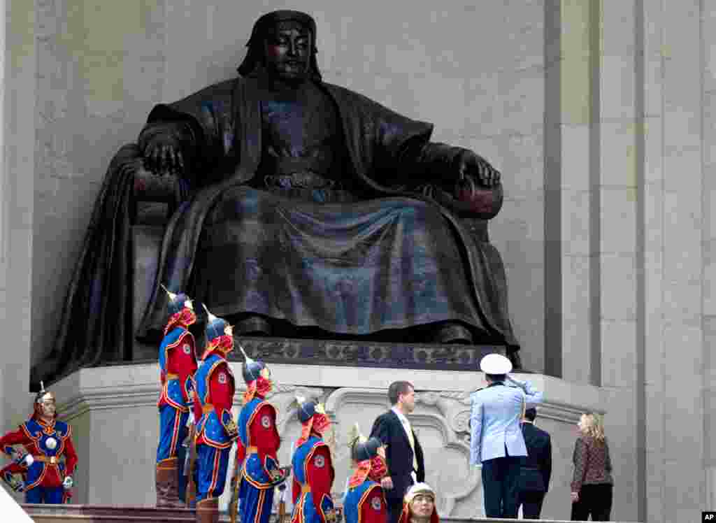 Clinton, right, under a statue of Chenggis Khan during her arrival ceremony at the Parliament House in Ulaanbaatar, Mongolia, July 9, 2012.