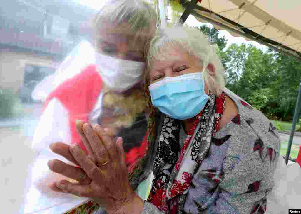 Lily Hendrickx, 83, a resident at Belgian nursing home &quot;Le Jardin de Picardie&quot; hugs Marie-Christine Desoer, the director of the residence, through a wall made with plastic sheets to protect against potential coronavirus disease (COVID-19) infection, in Peruwelz, Belgium, July 1, 2020.&nbsp;