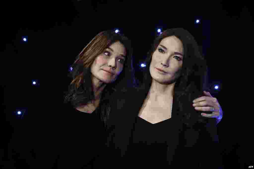 French-Italian model and singer Carla Bruni poses next to a wax sculpture depicting herself during its inauguration on Dec.17, 2018 at the Musee Grevin wax museum in Paris.