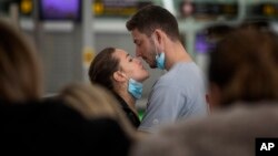 Sepasang muda-mudi tampak menarik masker mereka dan berciuman di bandara di tengah perebakan wabah virus corona (foto: ilustrasi). 