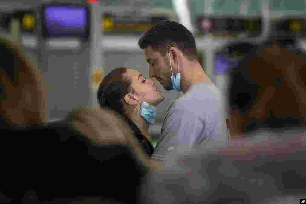 A couple kisses at the Barcelona airport, Spain.