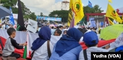 Seorang anak membawa atribut kampanye pasangan capres cawapres nomor urut 02 di tengah lokasi kampanye capres 02, Prabowo di Solo, Rabu, 10 April 2019. (Foto: VOA/Yudha)