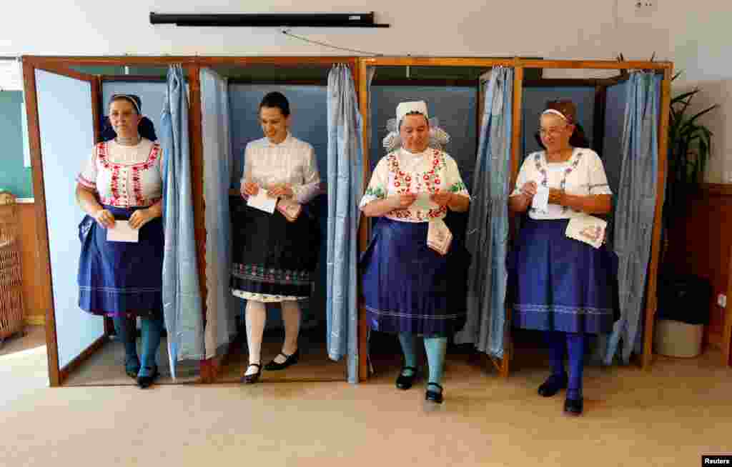 Hungarian women wearing traditional costume leave a voting booth at a polling station during a referendum on EU migrant quotas in Veresegyhaz, Oct. 2, 2016.