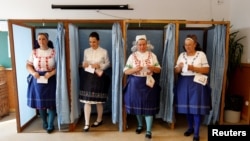 Hungarian women wearing traditional costume leave a voting booth at a polling station during a referendum on EU migrant quotas, Oct. 2, 2016. Both sides claimed victory as the vote was declared not valid.