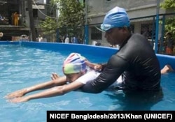 An instructor teachers a boy to swim in Bangladesh, 2013. (Photot Courtesy of UNICEF/Khan)