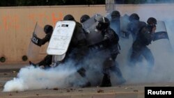 Policías reaccionan al gas lacrimógeno arrojado por un partidario de Salvador Nasralla, candidato presidencial opositor durante una manifestación el 30 de noviembre de 2017.