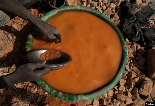 An artisanal miner pans for gold using a plastic wash basin and metal pan at an unlicensed mine near the city of Doropo, Ivory Coast, Feb. 13, 2018.