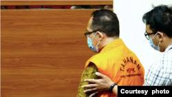 Petugas KPK mengarahkan Hakim Itong Isnaeni Hidayat agar tenang dalam konferensi pers mengenai Operasi Tangkap Tangan (OTT) di Pengadilan Negeri Surabaya, di Jakarta, pada 20 Januari 2022. (Foto: Tangkapan layar)