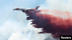 A plane drops fire-retardant chemicals on the 416 Fire near Durango, Colorado, June 9, 2018.
