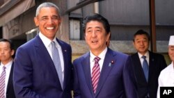 Mantan Presiden AS Barack Obama (kiri) dan PM Jepang Shinzo Abe berpose di depan restoran sushi "Kyubey" di Ginza, Tokyo, Minggu (25/3). 