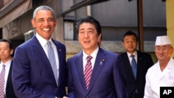 Mantan Presiden AS Barack Obama (kiri) dan Perdana Menteri Jepang Shinzo Abe berpose di depan restoran sushi, Kyubey, di distrik pusat perbelanjaan di Tokyo, 25 Maret 2018. 