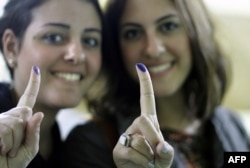 Egyptian women show their inked fingers after voting in Cairo, Egypt, Monday, Nov. 28, 2011