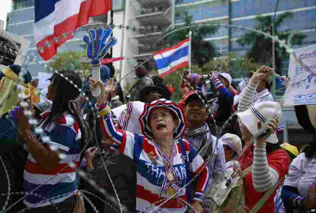 Anti-government protesters shout slogans demanding Thai Prime Minister Yingluck Shinawatra step down during a protest outside her temporary office, Bangkok, Thailand, Feb. 19, 2014.