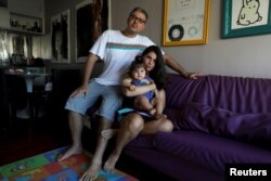 Tatiana Barcellos, 37 tahun, pegawai negeri di Kantor Jaksa Federal, bersama bayinya yang berusia 8 bulan, Alice, dan suaminya, Marcelo Valenca, 39 tahun, pada hari pertama Tatiana kembali bekerja, di Rio de Janeiro, Brasil, 28 Januari 2019.