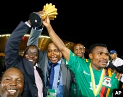 Zambia's captain Christopher Katongo, right, and Zambia Football President Kalusha Bwalya, second right, hold up the Africa Cup trophy after their victory over Ivory Coast in Libreville, Gabon, Feb. 12, 2012.