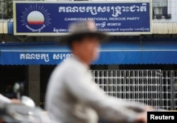 FILE - A man rides a motorcycle past the Cambodia National Rescue Party (CNRP) headquarters in Phnom Penh, Nov. 17, 2017.