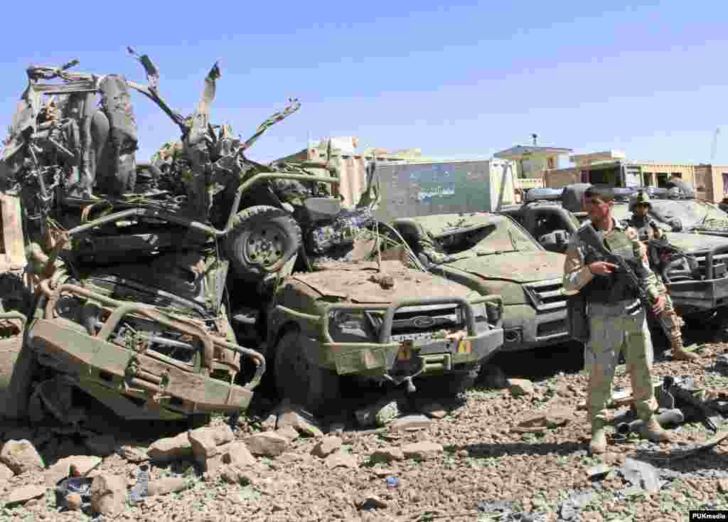 Members of the Afghan security force keep watch at the site of a suicide bomb attack in Ghazni Province. Taliban insurgents detonated two powerful truck bombs outside the office of the spy agency and a police compound, killing 18 people and wounding around 150.