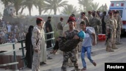 An Iraqi soldier carries a girl displaced by fighting in Ramadi across a bridge at the outskirts of Baghdad, May 19, 2015. 