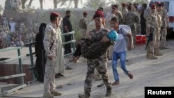 An Iraqi soldier carries a girl displaced by fighting in Ramadi across a bridge at the outskirts of Baghdad, May 19, 2015. 